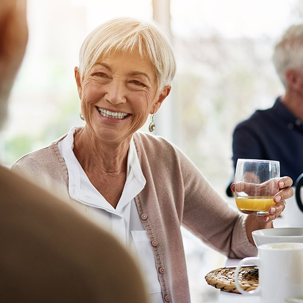 Senior-aged Residence at Wellpoint community member sitting at table with glass of wine